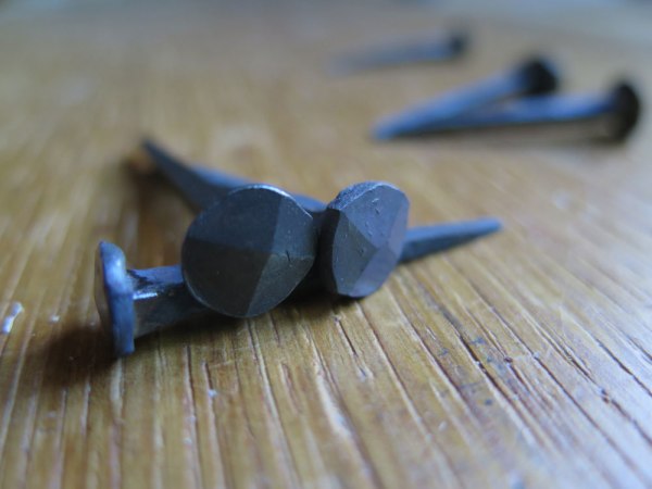 The diamond-pattern head of a blacksmith nail (right) and a machine-made one.