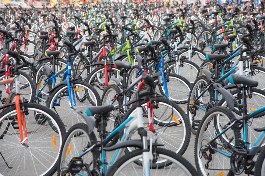 Many bicycles sit together in a town square