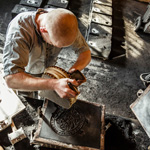 A metal worker makes a mold from a historical pattern at a museum