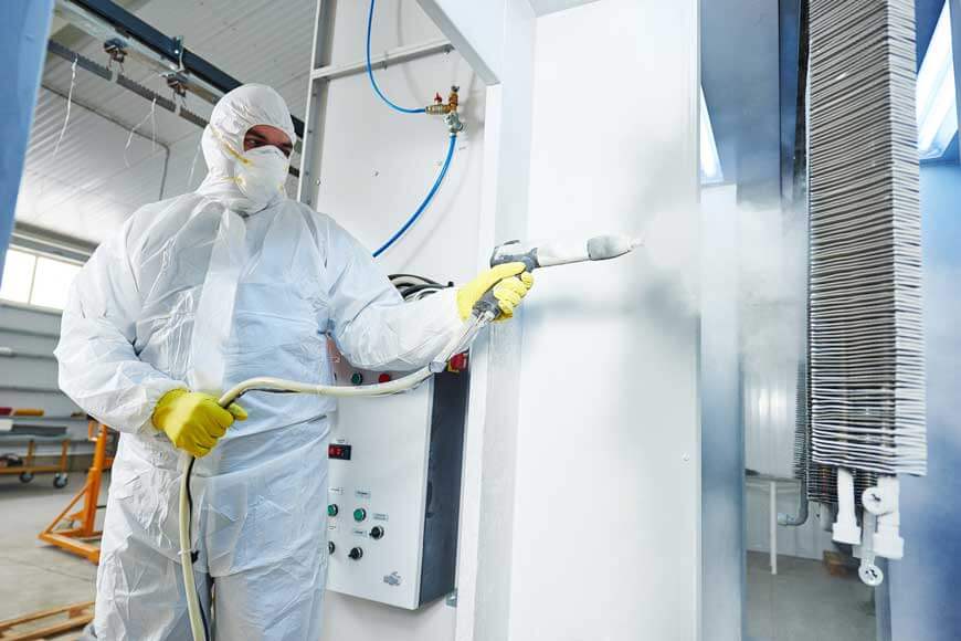 Dry powder being applied to metal parts in a powder coating shop