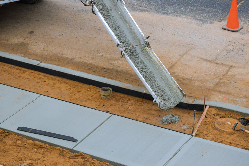 A concrete truck dumps wet cement over a rebar grid