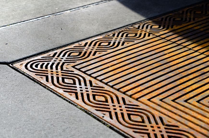 Raw cast iron tree grate with an oscillating edge pattern