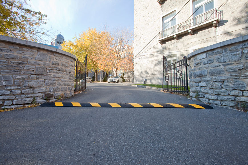 speed bump in driveway before decorative gate in stonework wall