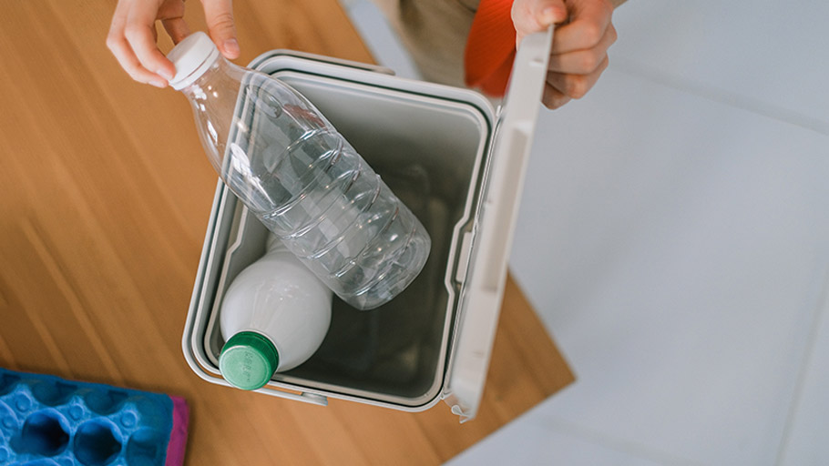 Plastic bottles being placed in a small bin for recycling